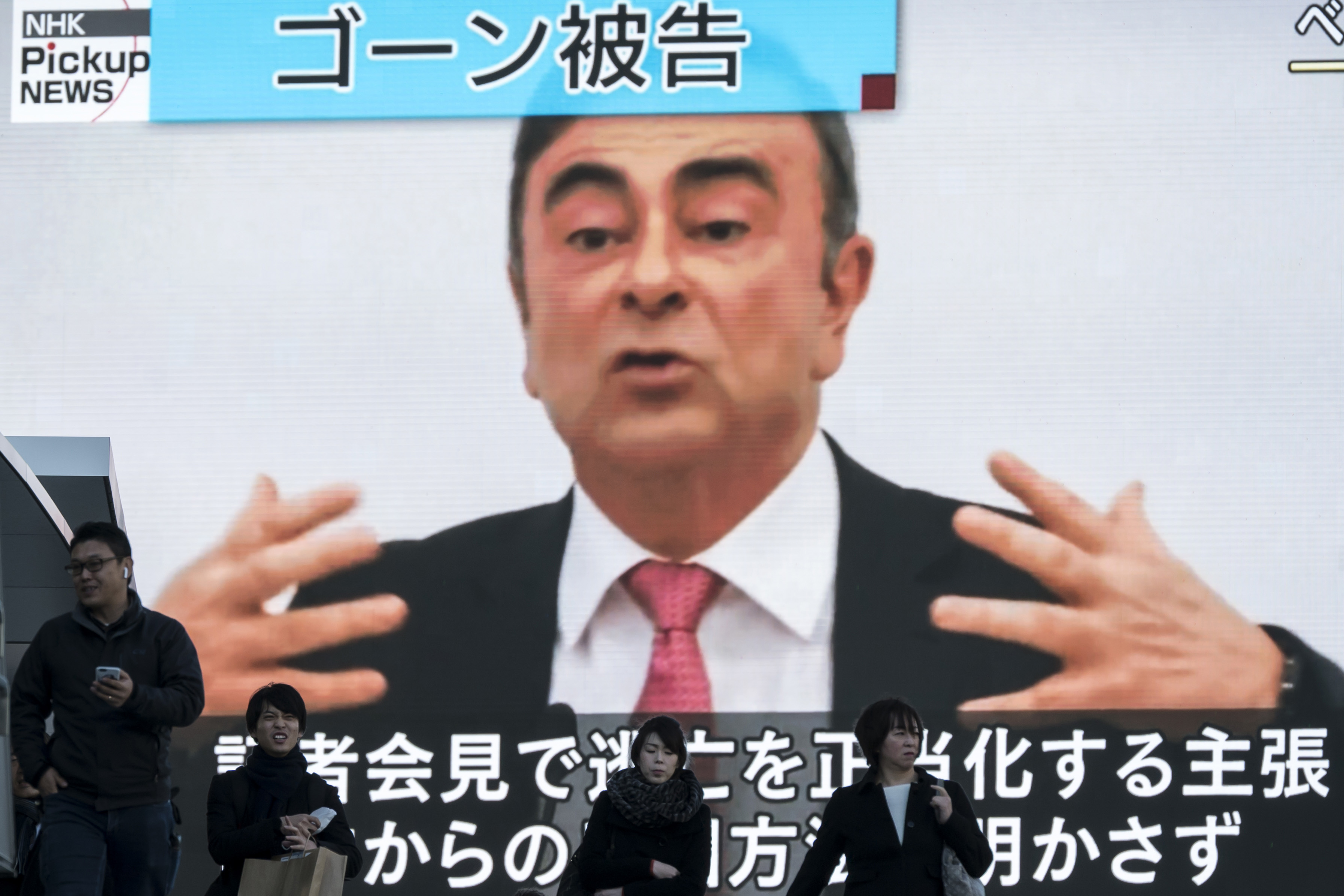 TOKYO, JAPAN - JANUARY 09: Pedestrians walk in front of a monitor displaying a news broadcast on former Nissan Motor Co. Chairman Carlos Ghosn on January 09, 2020 in Tokyo, Japan. Ghosn was awaiting trial in Japan on charges of financial crimes when he fled house arrest in Tokyo, arriving in Beirut on December 30. (Photo by Tomohiro Ohsumi/Getty Images)