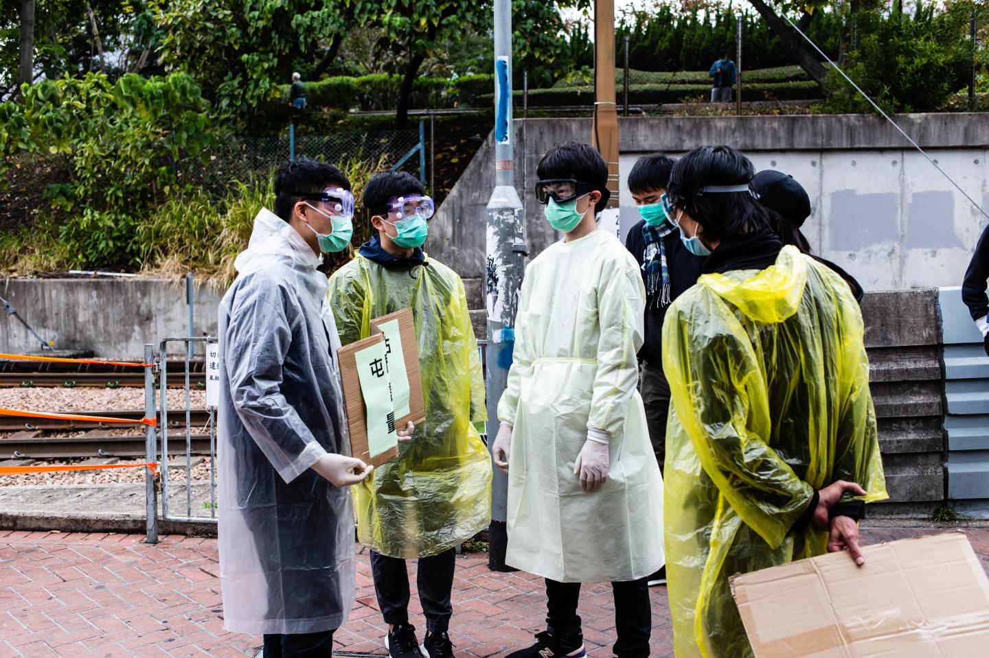 TUEN MUN, HONG KONG, CHINA - 2020/02/04: Volunteers wear surgical masks and raincoats as part of sanitary precautions. In light of a coronavirus outbreak in China, Hong Kong district councillors and residents formed makeshift quarantine stations, screening passengers arriving from China. Citizens measured passenger's temperatures and offered hand sanitizer. (Photo by Willie Siau/SOPA Images/LightRocket via Getty Images)