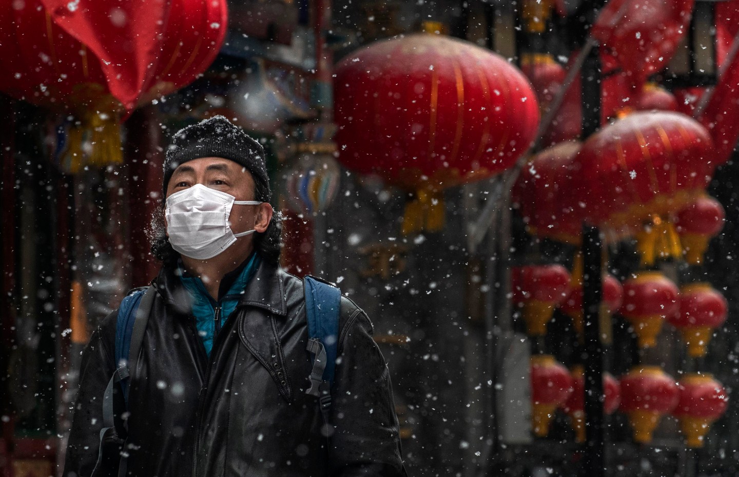 BEIJING, CHINA - FEBRUARY 05: A Chinese man wears a protective mask as he walks during a snowfall in an empty and shuttered commercial street on February 5, 2020 in Beijing, China. China's stock markets tumbled in trading on Monday, the first day back after an extended Lunar New Year holiday as a mystery virus continues to spread in China and worldwide. The number of cases of a deadly new coronavirus rose to more than 20000 in mainland China Wednesday, days after the World Health Organization (WHO) declared the outbreak a global public health emergency. China continued to lock down the city of Wuhan in an effort to contain the spread of the pneumonia-like disease which medicals experts have confirmed can be passed from human to human. In an unprecedented move, Chinese authorities have put travel restrictions on the city which is the epicentre of the virus and neighbouring municipalities affecting tens of millions of people. The number of those who have died from the virus in China climbed to over 490 on Thursday, mostly in Hubei province, and cases have been reported in other countries including the United States, Canada, Australia, Japan, South Korea, India, the United Kingdom, Germany, France and several others. The World Health Organization has warned all governments to be on alert and screening has been stepped up at airports around the world. Some countries, including the United States, have put restrictions on Chinese travellers entering and advised their citizens against travel to China. (Photo by Kevin Frayer/Getty Images)