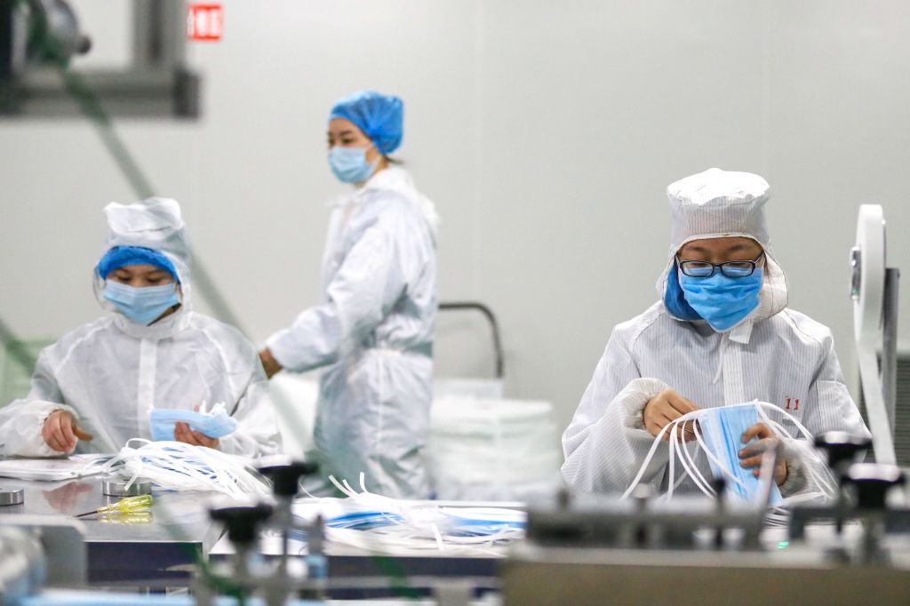 Workers protective suits prepare surgical masks at a factory in China during the Wuhan coronavirus outbreak.