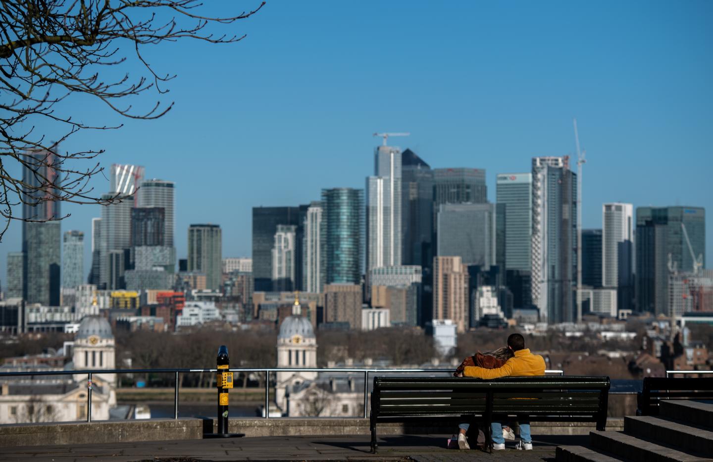 LONDON, ENGLAND - FEBRUARY 12: A couple sit on a bench in the morning sun in Greenwich park with Canary Wharf seen in the distance on February 12, 2020 in London, England. High winds, rain and snow from Storm Ciara has brought damage and disruption to public transport and communities across the United Kingdom this week. Storm Dennis is expected to arrive later in the week and with it bringing more widespread strong winds and heavy rain. (Photo by Chris J Ratcliffe/Getty Images)LONDON, ENGLAND - FEBRUARY 12: A couple sit on a bench in the morning sun in Greenwich park with Canary Wharf seen in the distance on February 12, 2020 in London, England. High winds, rain and snow from Storm Ciara has brought damage and disruption to public transport and communities across the United Kingdom this week. Storm Dennis is expected to arrive later in the week and with it bringing more widespread strong winds and heavy rain. (Photo by Chris J Ratcliffe/Getty Images)