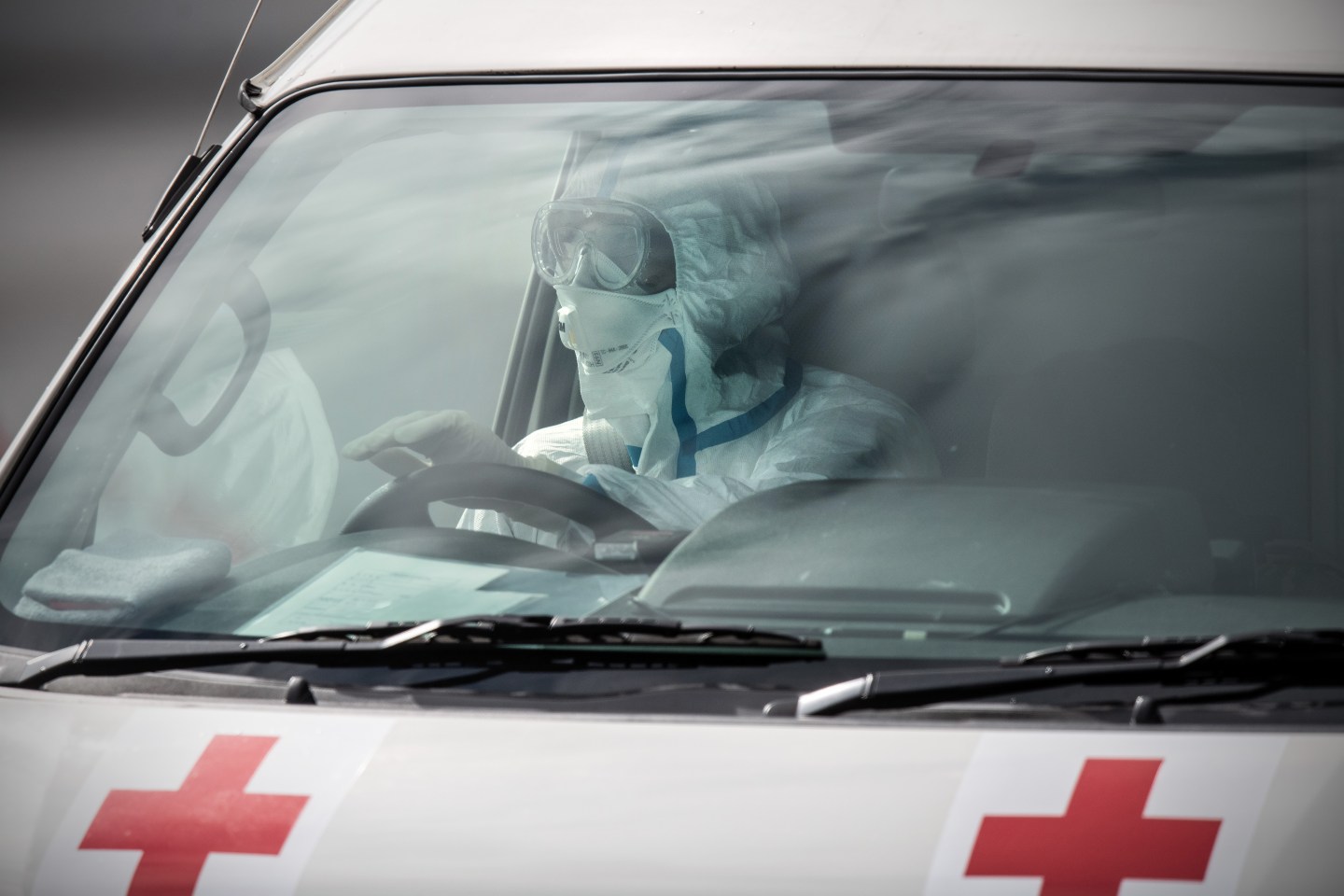 An emergency worker in protective clothing drives an ambulance carrying a person diagnosed with Covid-19 from the Diamond Princess cruise ship, on Feb. 13, 2020 in Yokohama, Japan.
