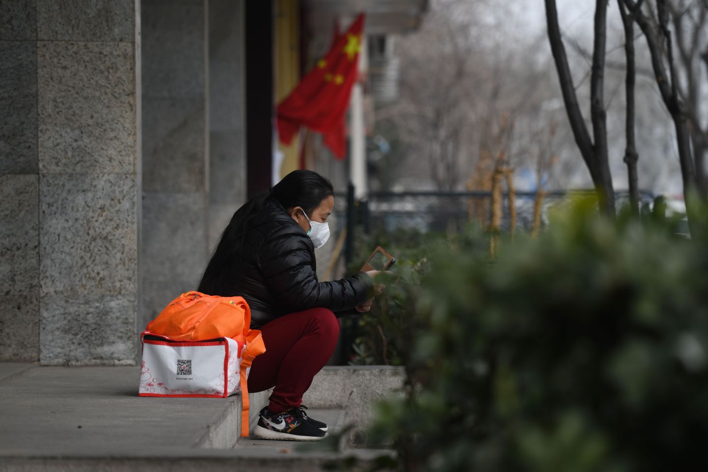 A woman wears a face mask as a preventive measure against the Covid-19 coronavirus as she looks at her mobile phone near the entrance of the Peking University People's Hospital in Beijing on Feb. 21, 2020.