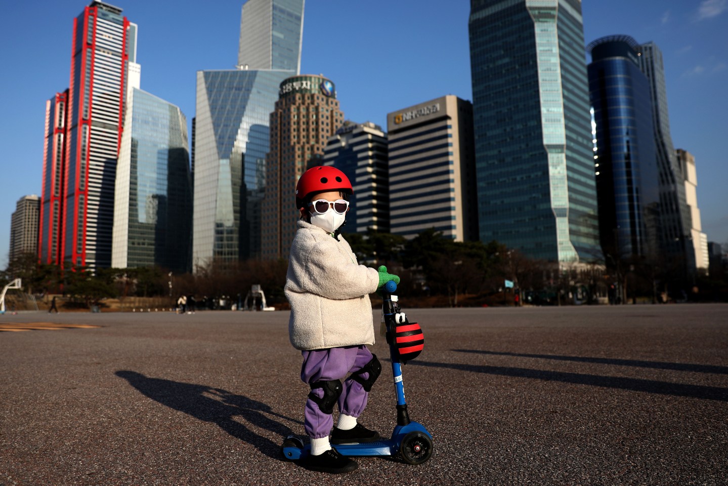A South Korean child wears a mask to prevent catching the coronavirus (COVID-19) while riding a scooter on February 27, 2020 in Seoul, South Korea.