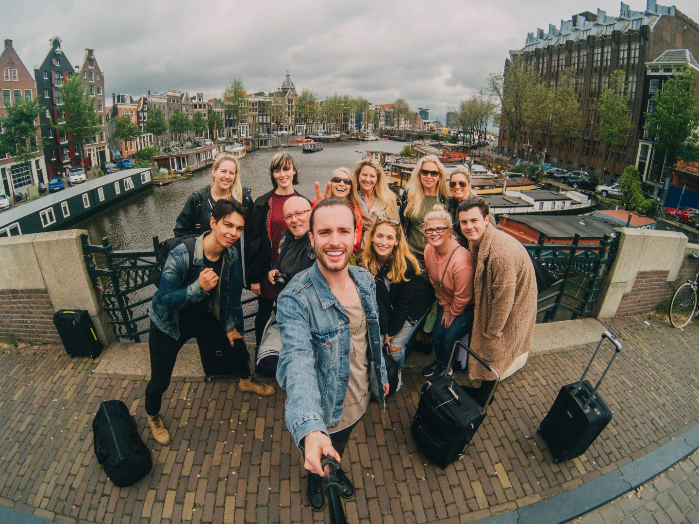 Group of friends taking a Selfie as they stand by the canal in Amsterdam. They are using a Selfie stick and action camera