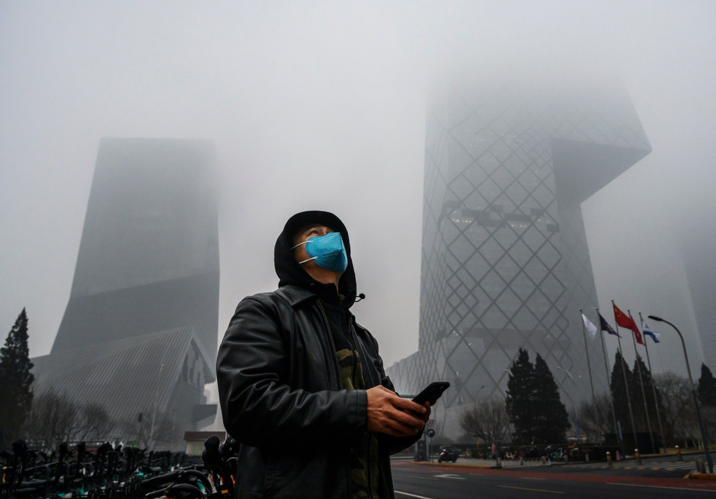 BEIJING, CHINA - FEBRUARY 13: A Chinese man wears a protective mask as he stands near the CCTV building in fog and pollution during rush hour in the central business district on February 13, 2020 in Beijing, China. The number of cases of the deadly new coronavirus COVID-19 rose to more than 52000 in mainland China Thursday, in what the World Health Organization (WHO) has declared a global public health emergency. China continued to lock down the city of Wuhan in an effort to contain the spread of the pneumonia-like disease which medicals experts have confirmed can be passed from human to human. In an unprecedented move, Chinese authorities have maintained and in some cases tightened the travel restrictions on the city which is the epicentre of the virus and also in municipalities in other parts of the country affecting tens of millions of people. The number of those who have died from the virus in China climbed to over 1300 on Thursday, mostly in Hubei province, and cases have been reported in other countries including the United States, Canada, Australia, Japan, South Korea, India, the United Kingdom, Germany, France and several others. The World Health Organization has warned all governments to be on alert and screening has been stepped up at airports around the world. Some countries, including the United States, have put restrictions on Chinese travellers entering and advised their citizens against travel to China. (Photo by Kevin Frayer/Getty Images)