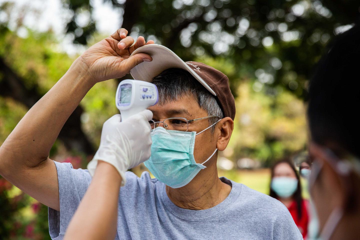 BANGKOK, THAILAND - MARCH 03: Thai are temperature scanned before receiving a free face mask at The Ministry of Public Health to receive one free surgical mask per person on March 3, 2020 in Bangkok, Thailand. Thailand reported its first Covid-19 related death on Saturday, February 29. On Sunday, Thailand's Public Health Ministry, redesignated Covid-19 as a dangerous communicable disease, allowing Thai authorities to take more drastic measures to fight the virus. Thai people have been standing in queues at pharmacies hoping to purchase more face masks and hand sanitizing gel to help protect themselves, but are currently only able to find masks at government handout stations. (Photo by Lauren DeCicca/Getty Images)
