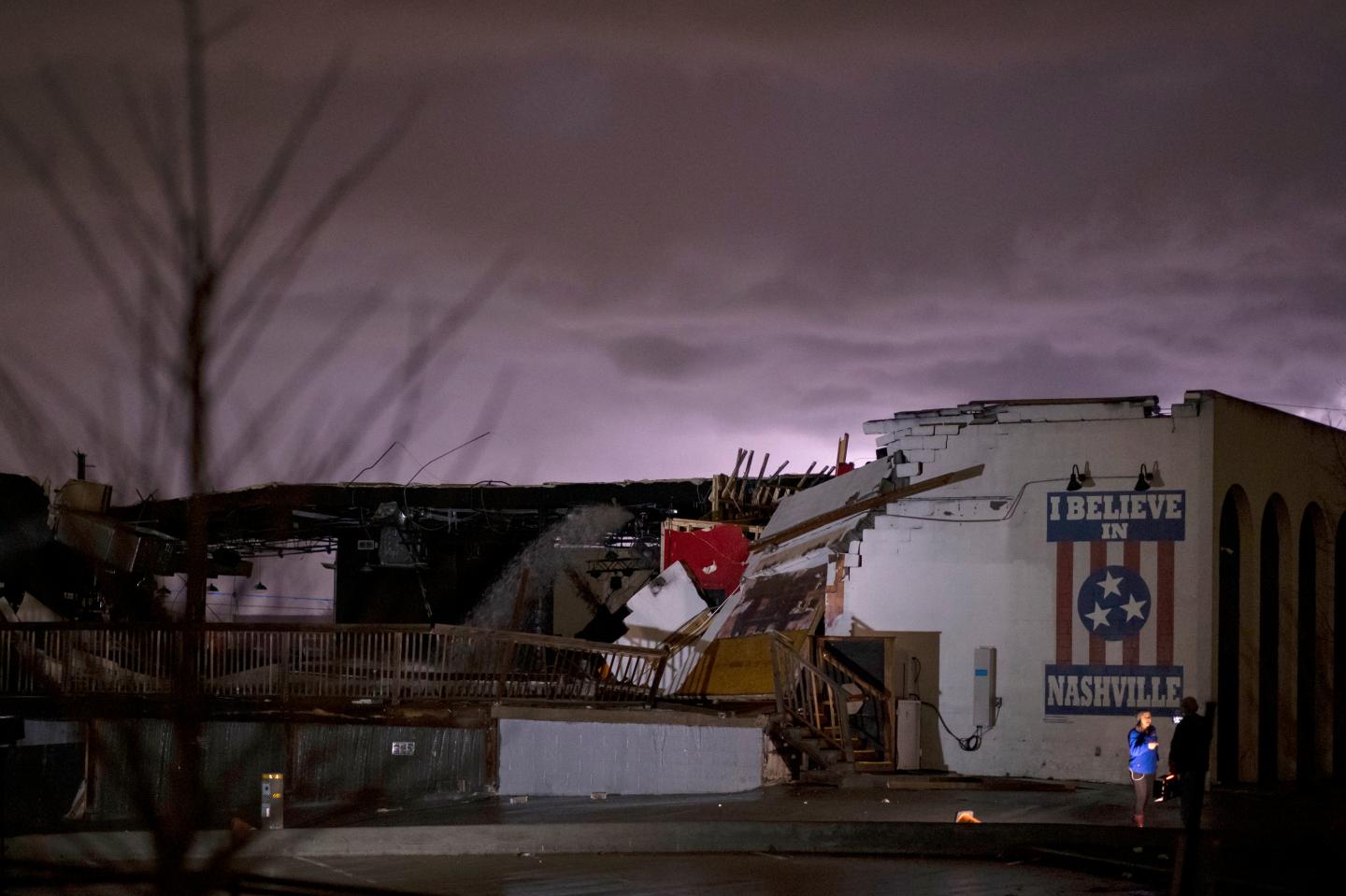NASHVILLE, TN - MARCH 03: A television news crew works in front of a mural on heavily damaged The Basement East in the East Nashville neighborhood as lightning strikes in the background on March 3, 2020 in Nashville, Tennessee. A tornado passed through Nashville just after midnight leaving a wake of damage in its path including two people killed in East Nashville. (Photo by Brett Carlsen/Getty Images)