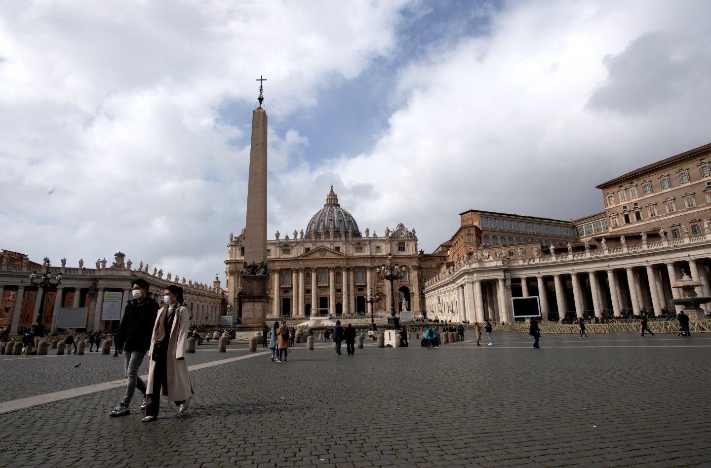 Tourists wearing a protective mask walk in St. Peter's square at the Vatican on March 03, 2020. - Italy urged tourists spooked by the coronavirus not to stay away, but efforts to reassure the world it was managing the outbreak were overshadowed by confusion over case numbers. Hotel bookings in Milan have plummeted to 20 percent, compared to nearly 90 percent normally at this time of year, while in Rome, far from the northern hotspots over 50 percent of bookings have been cancelled until the end of March, hotel association Federalberghi said. (Photo by Tiziana FABI / AFP) (Photo by TIZIANA FABI/AFP via Getty Images)