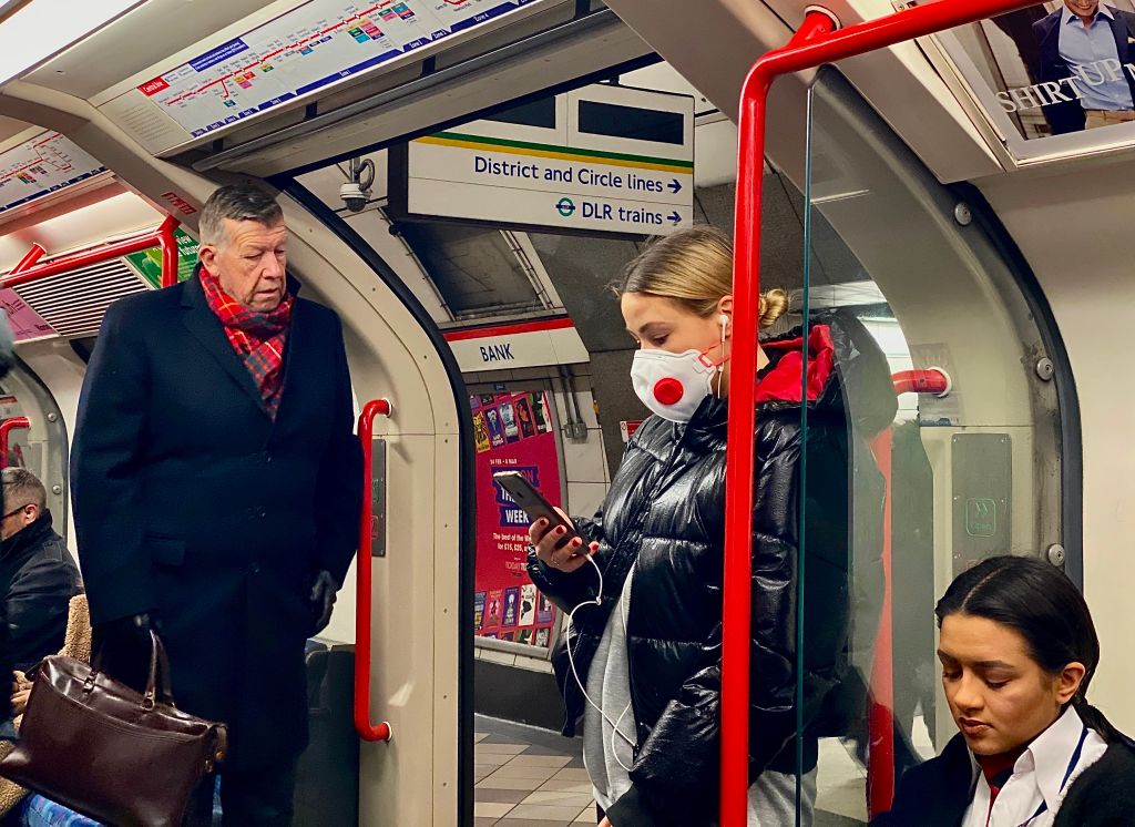 A woman wears a protective face mask as she travels on a London tube train carriage at Bank Underground station. The British city is seeing a rising number of coronavirus cases.