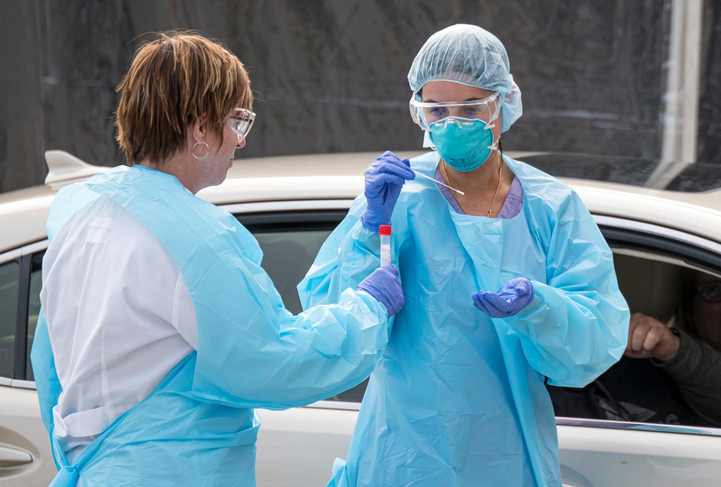 Medical personnel collect a sample from a patient at a drive-thru COVID-19 testing clinic at a Kaiser Permanente facility in San Francisco on March 12, 2020.