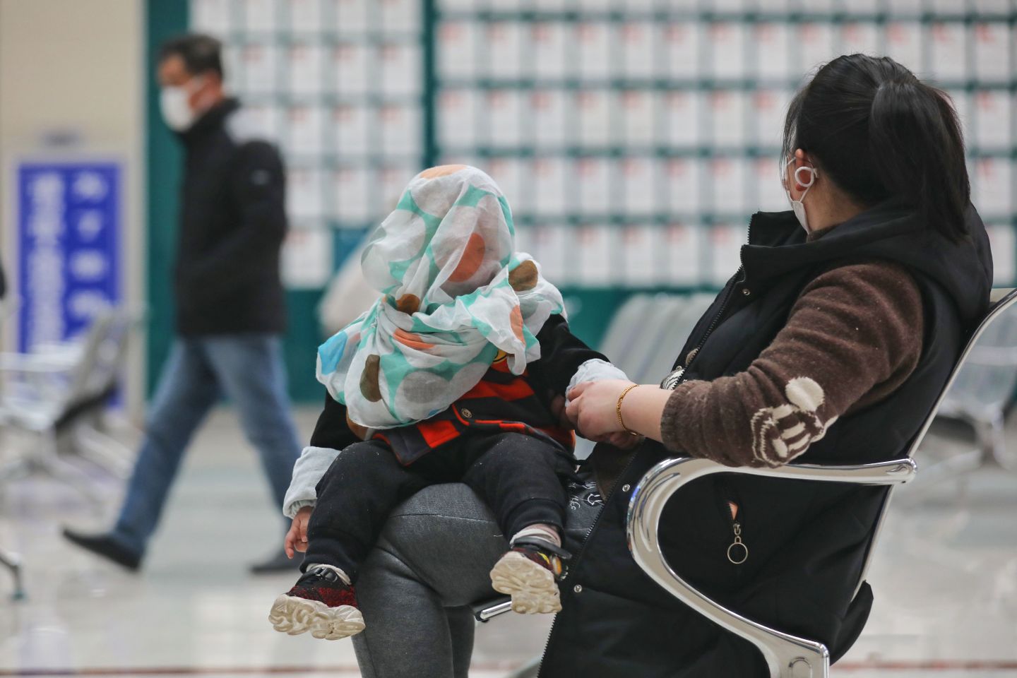 A woman visits a hospital with a child in Wuhan, in China's central Hubei province on March 13, 2020. - China reported just eight cases of the coronavirus on March 13, with no new domestic infections outside the epicentre of Hubei province. (Photo by STR / AFP) / China OUT (Photo by STR/AFP via Getty Images)