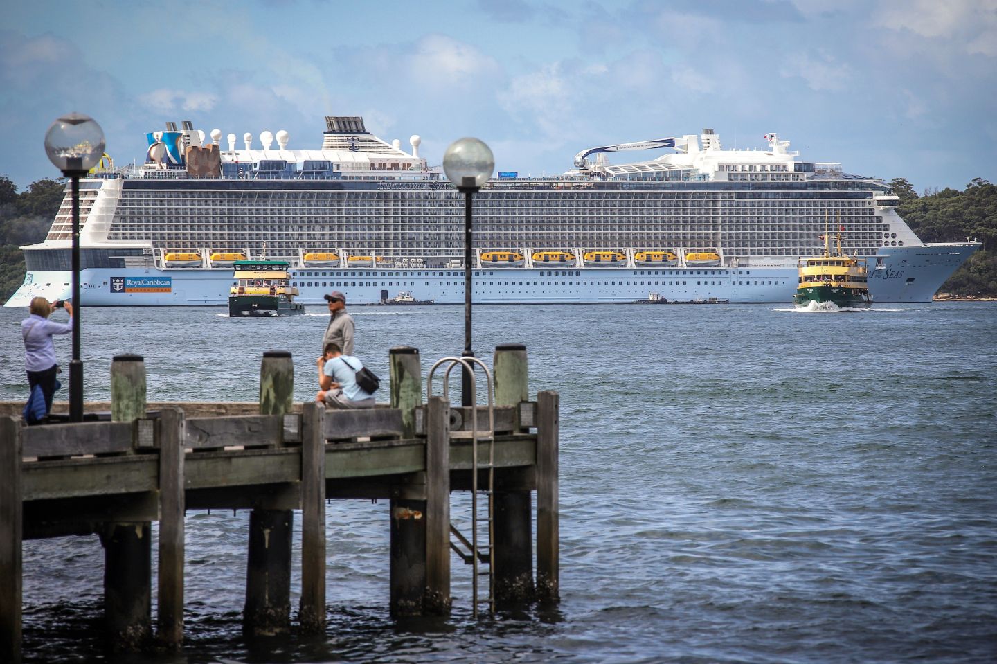 Tourists take photographs on the waterfront as a cruise ship sits moored in Sydney Harbour a day before its expected departure on March 17, 2020. - The Australian government said on March 15 it has banned international cruise ship arrivals for 30 days, based on the latest health advice and developments in the evolving COVID-19 coronavirus situation. (Photo by DAVID GRAY / AFP) (Photo by DAVID GRAY/AFP via Getty Images)