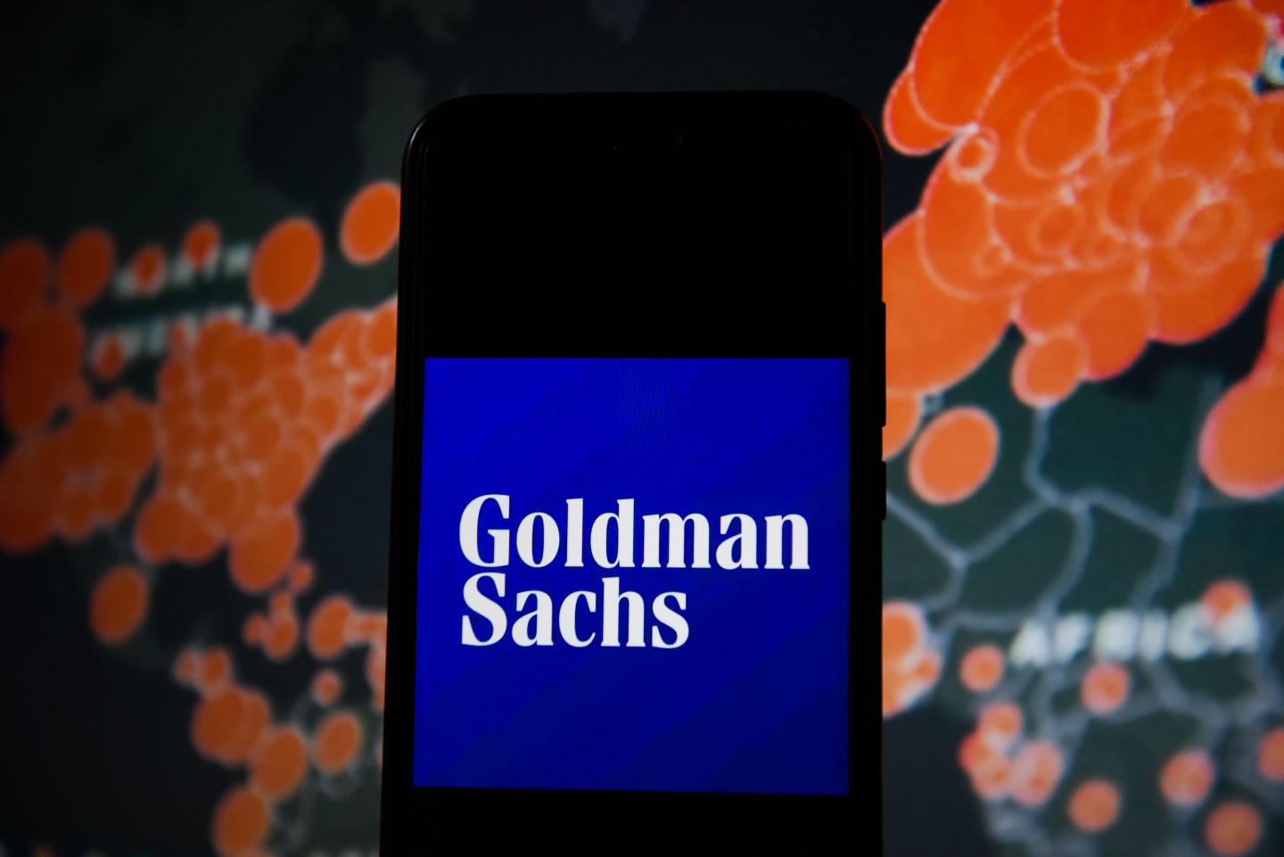POLAND - 2020/03/19: In this photo illustration a Goldman Sachs logo seen displayed on a smartphone with a World map of COVID 19 epidemic on the background. (Photo Illustration by Omar Marques/SOPA Images/LightRocket via Getty Images)