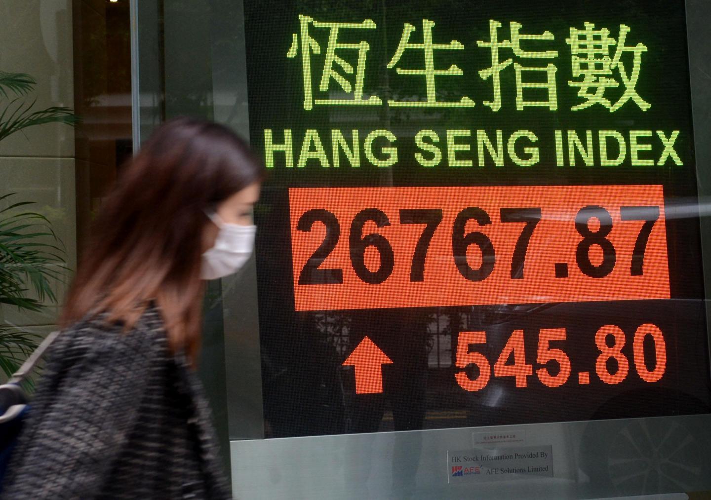 HONG KONG, CHINA - MARCH 05: A woman walks by an electronic screen displaying the Hang Seng index on March 5, 2020 in Hong Kong, China. (Photo by Deng Qingle/China News Service via Getty Images)