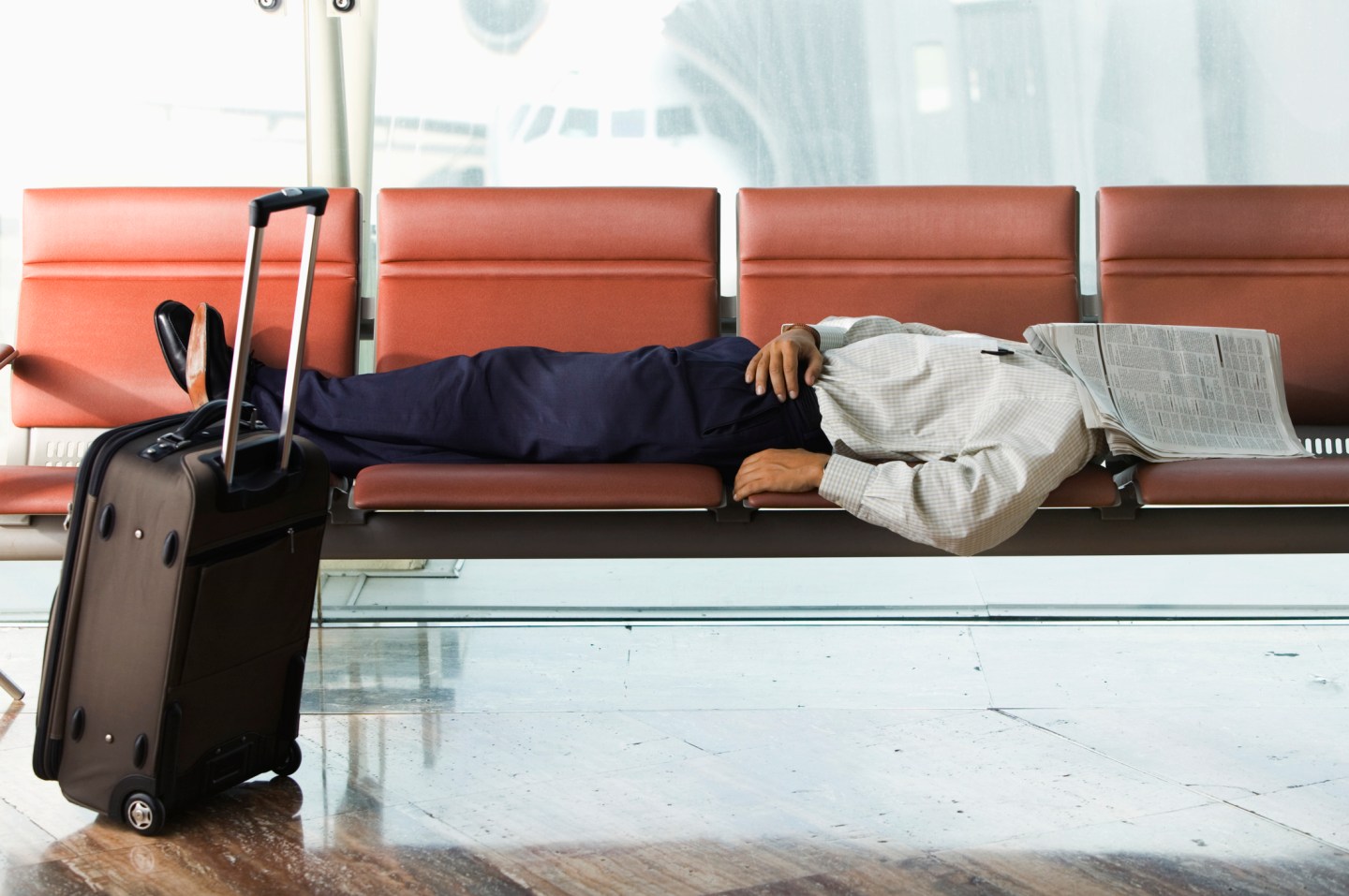 A man sleeping in an airport terminal, as so many of us have attempted to do while making connecting flights.