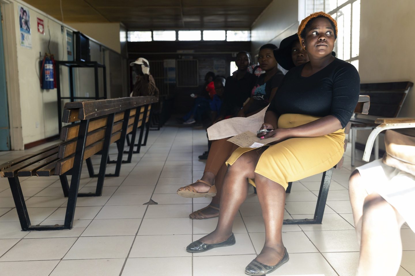 Patients sit on benches in a waiting room at Rutsanana Polyclinic in Glen Norah township, Harare, Zimbabwe, on June 24, 2019.