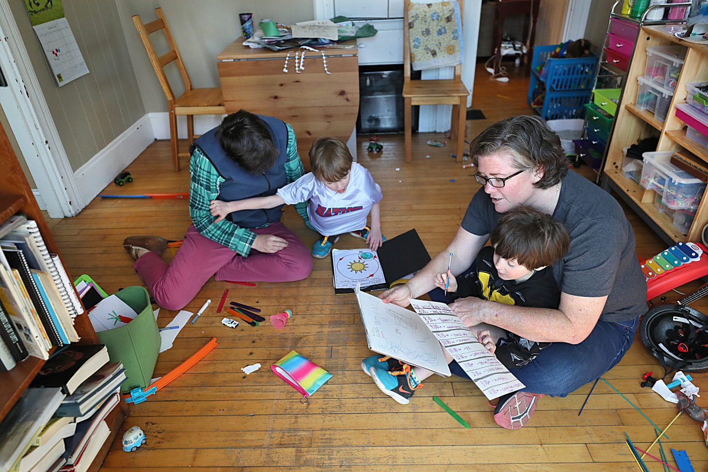 Jennifer Green, left, and Lisa Spalding, right, try some activities with their sons as they work from home in Natick, MA on March 18, 2020.