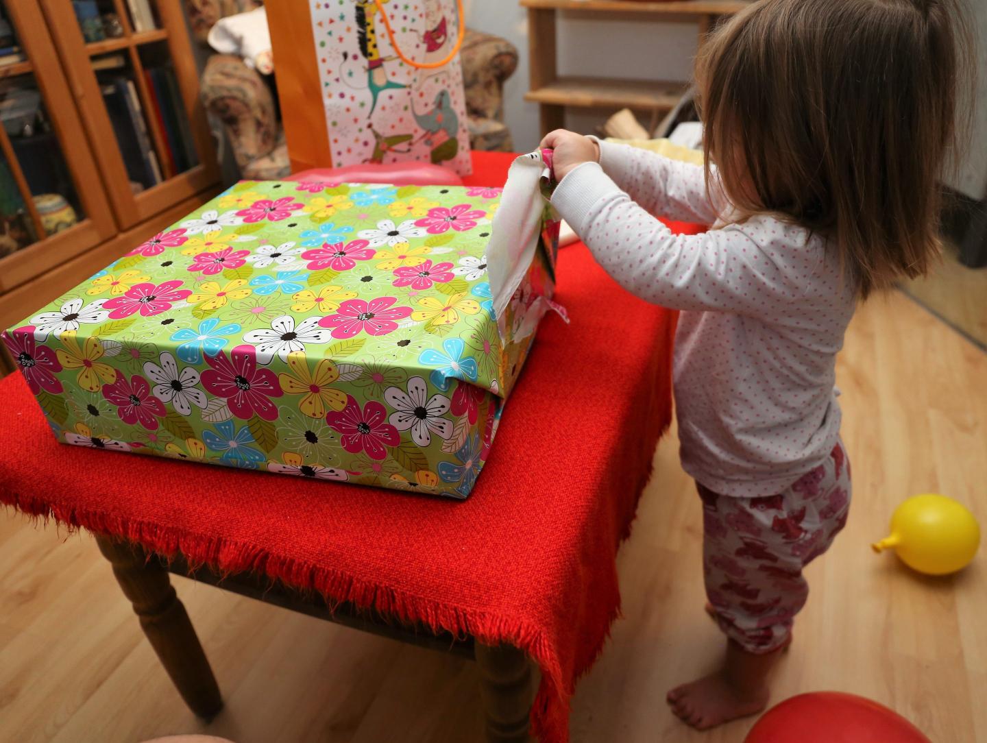 Full Length Of Cute Girl Opening Gift At Home