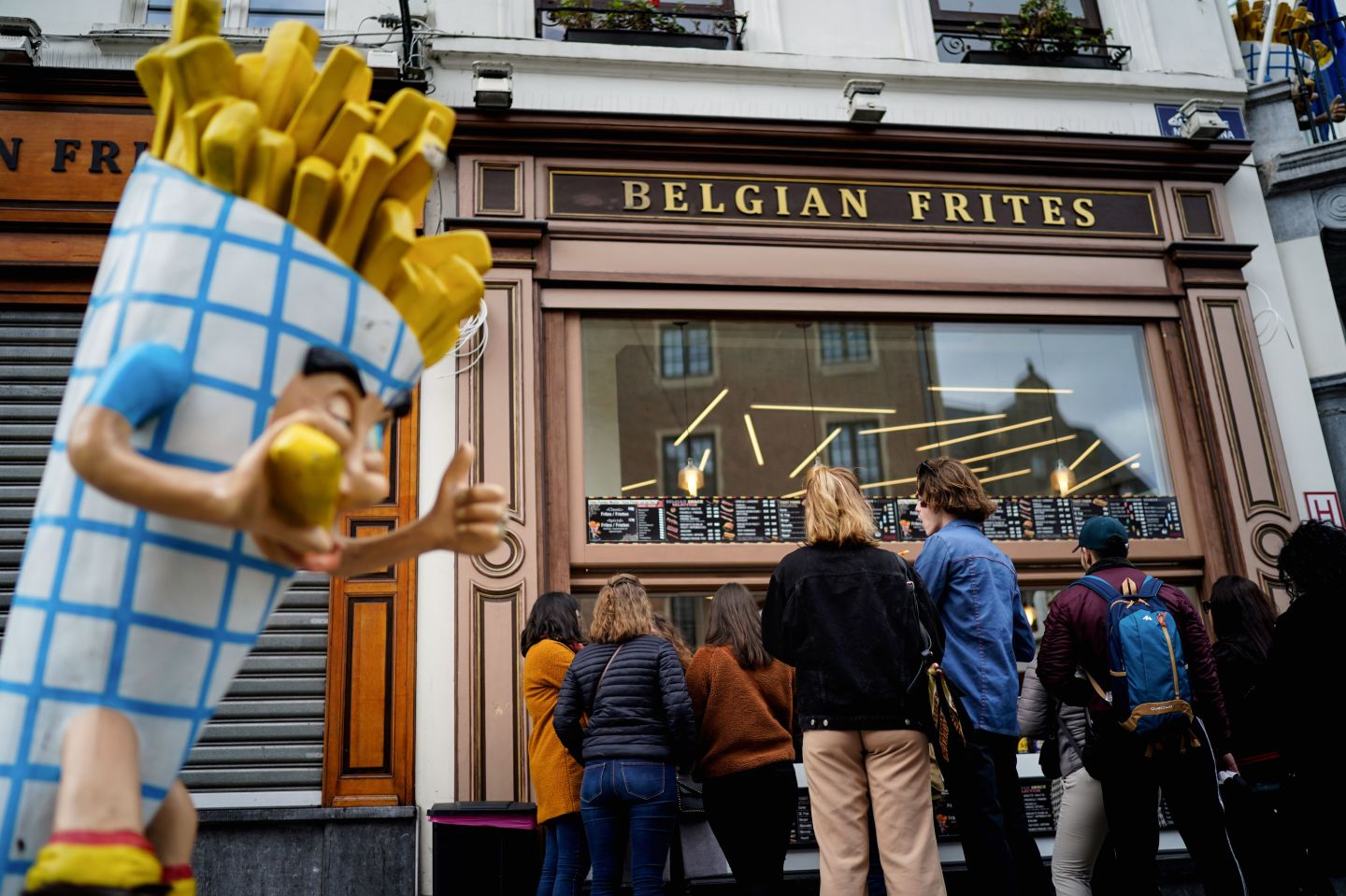 People stand in line in front of a French fries vendor near the Grand Place in central Brussels, on March 14, 2020, amid the outbreak of COVID-19, caused by the novel coronavirus.