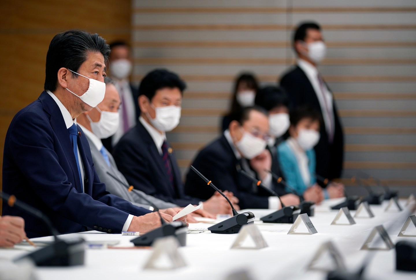 Japan's Prime Minister Shinzo Abe (L) speaks during a meeting at the headquarters for measures against the novel coronavirus disease, at the prime minister's official residence in Tokyo on April 6, 2020. - Abe said on April 6 the government plans to declare a state of emergency and proposed a stimulus package worth 1 trillion USD as new coronavirus infections spike in Tokyo and elsewhere. (Photo by Franck ROBICHON / POOL / AFP) (Photo by FRANCK ROBICHON/POOL/AFP via Getty Images)
