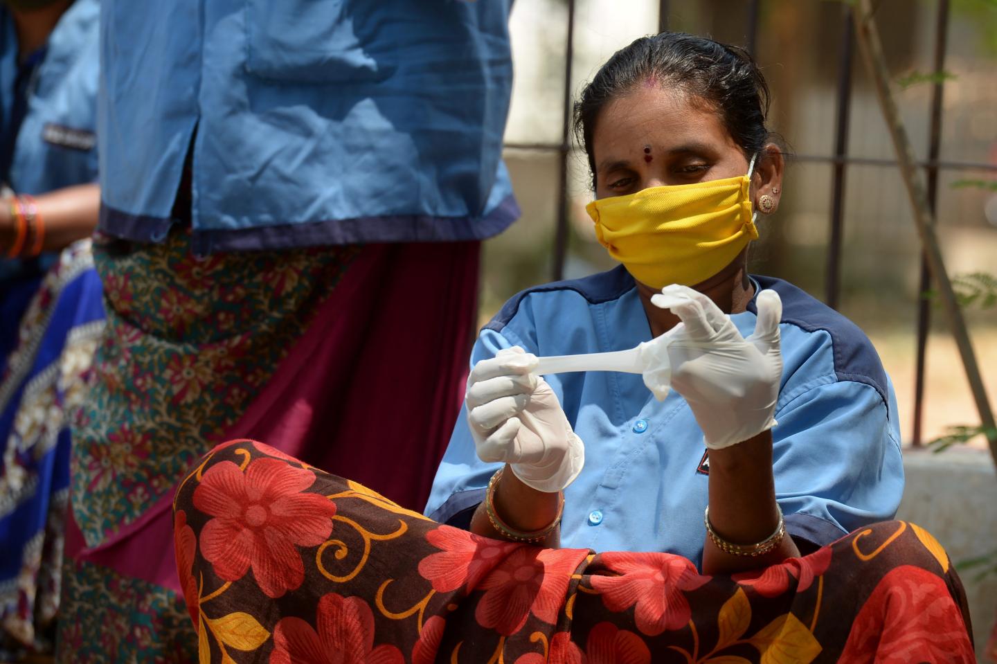 A street sweeper tries gloves distributed by the Directorate of Medical and Health Unit during a government-imposed nationwide lockdown as a preventive measure against the COVID-19 coronavirus, in Hyderabad on April 22, 2020. (Photo by NOAH SEELAM / AFP) (Photo by NOAH SEELAM/AFP via Getty Images)