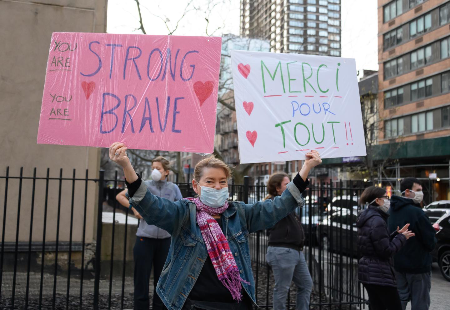 NEW YORK, NY - APRIL 06: A person holds up two signs, one in english and one in french reading, "You Are Strong, You Are Brave" and "Merci Pour Tout!!" near NYU Langone Health hospital to show their gratitude to medical staff and essential workers during the coronavirus pandemic on April 6, 2020 in New York City.