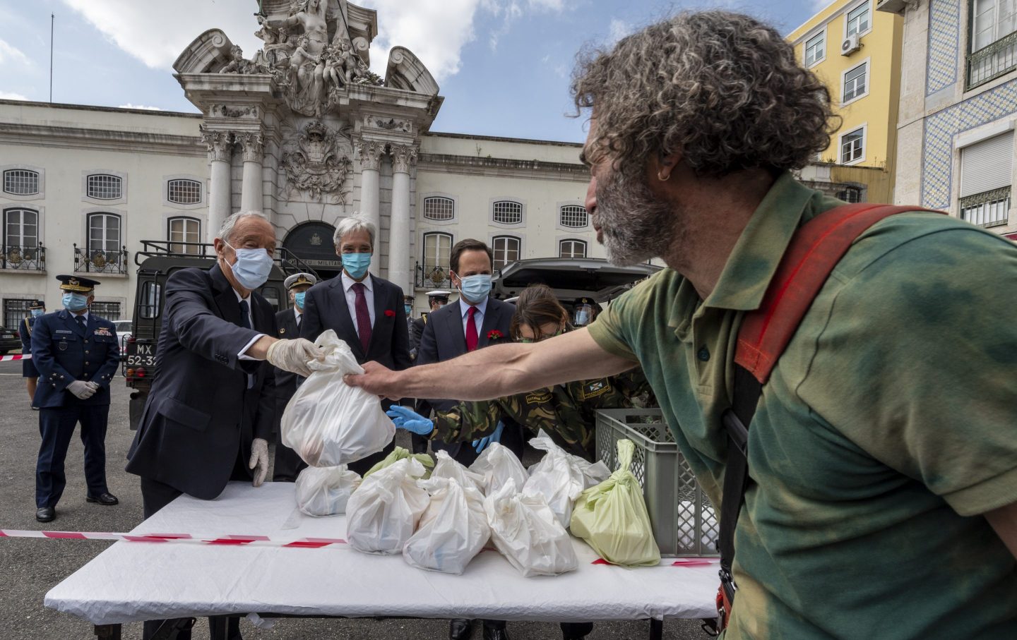 The Portuguese President Marcelo Rebelo de Sousa (L) is accompanied by the Minister of Defense João Gomes Cravinho (C) and Lisbon Mayor Fernando Medina (R) while while distributing food to a homeless at a post set up the Army in Santa Apolonia during the COVID-19 Coronavirus pandemic on April 25, 2020 in Lisbon, Portugal.