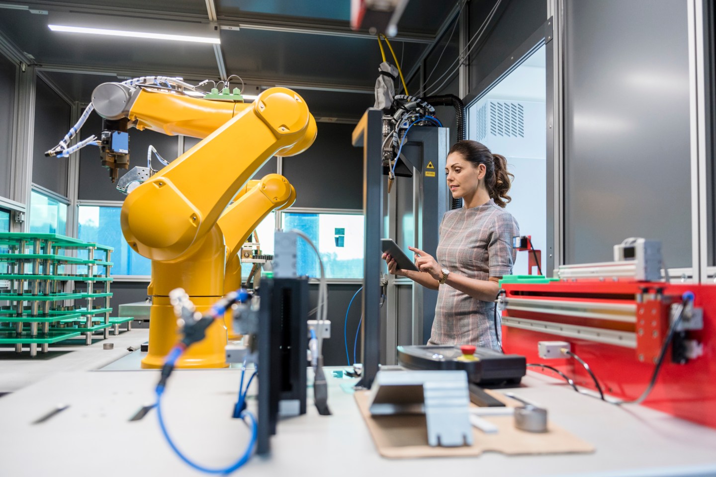 Woman supervising a robotic arm.