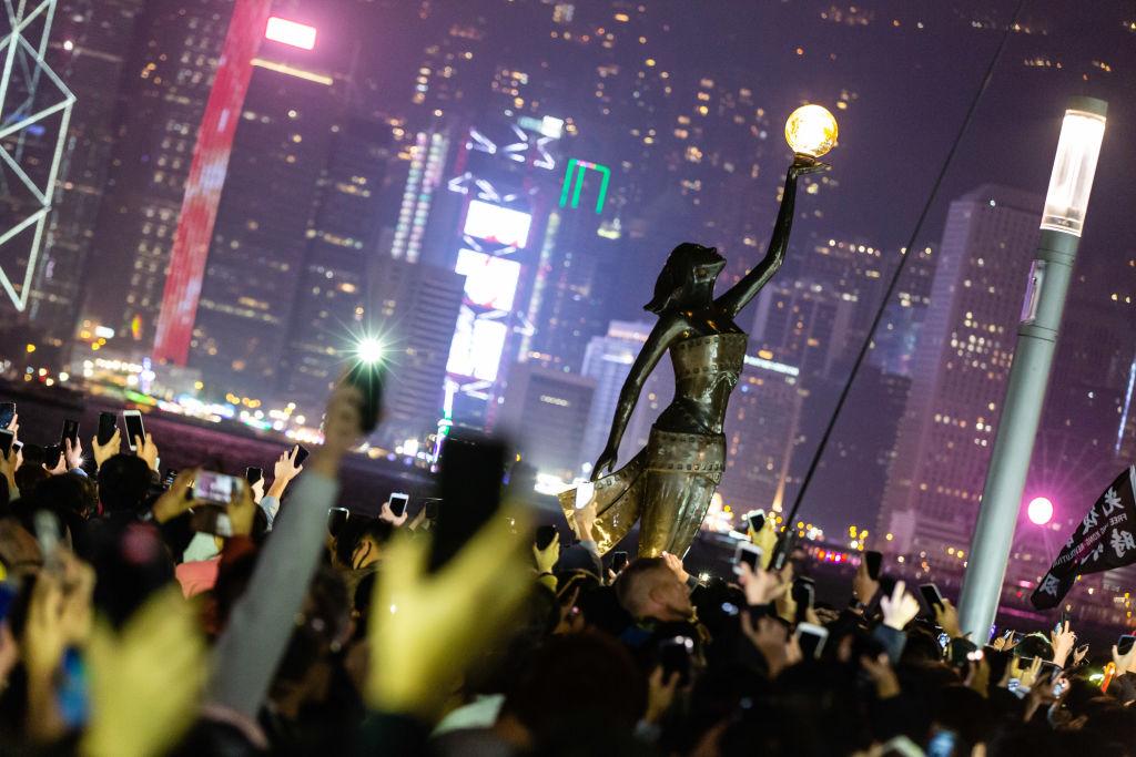 People flash phone lights at a statue during the
