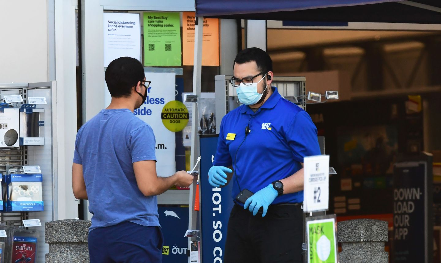 A Best Buy employee tends to a customer outside a store in Montebello, California on April 15, 2020 as the electronics nationwide chain store remains closed to customers but open for pickups. - Best Buy said it will furlough about 51,000 employees as coronavirus-related sales surge ends. (Photo by Frederic J. BROWN / AFP) (Photo by FREDERIC J. BROWN/AFP via Getty Images)