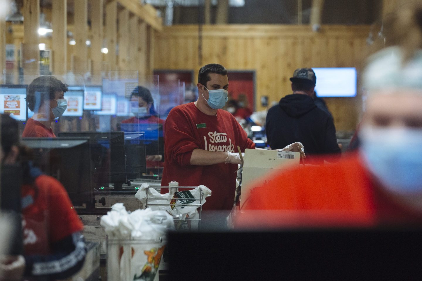 Workers wearing protective masks stand behind protective barriers at a Stew Leonard's supermarket in Paramus, New Jersey, U.S., on Tuesday, May 12, 2020.