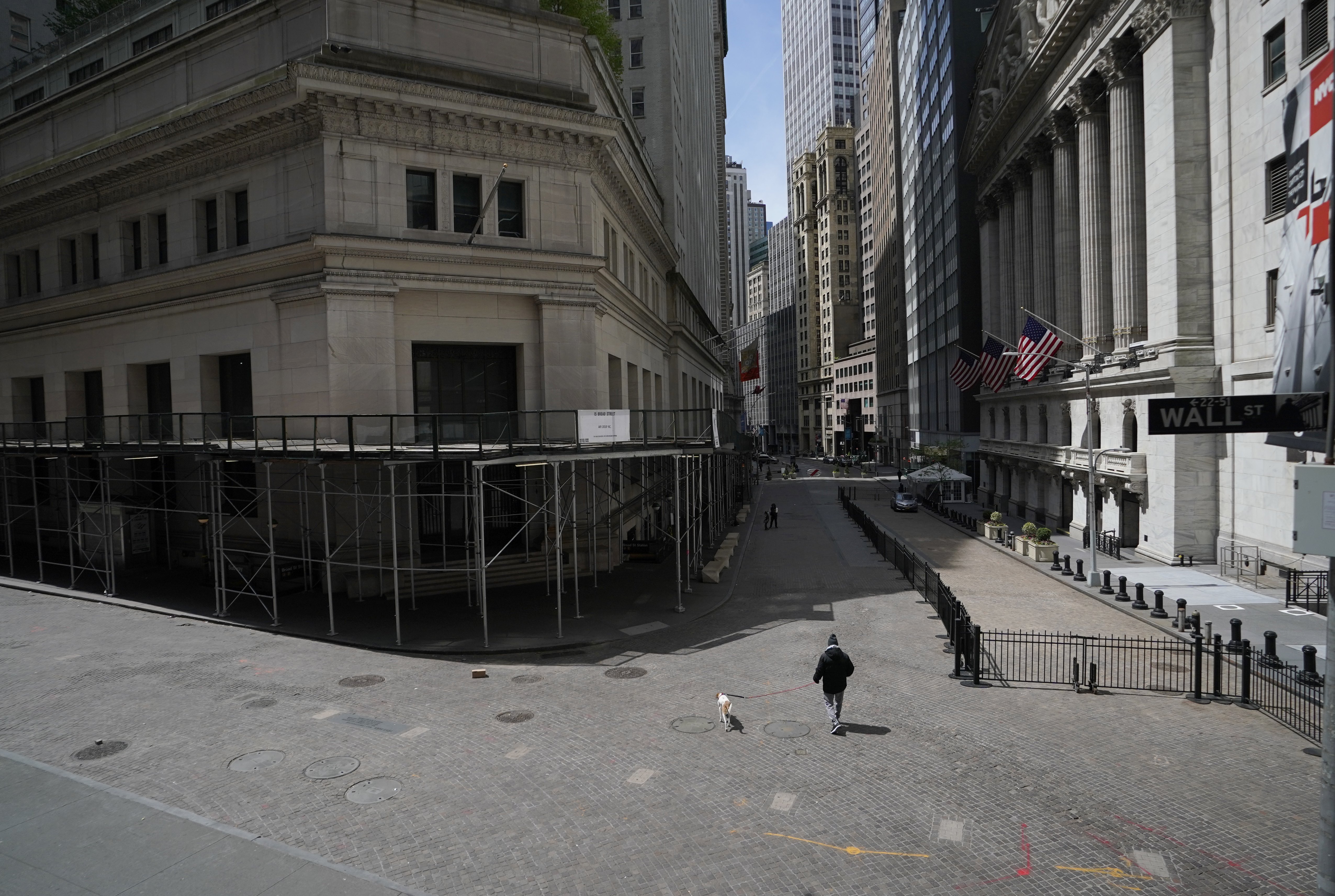 A person walks their dog in the empty streets in front of the New York Stock Exchange on May 19, 2020.