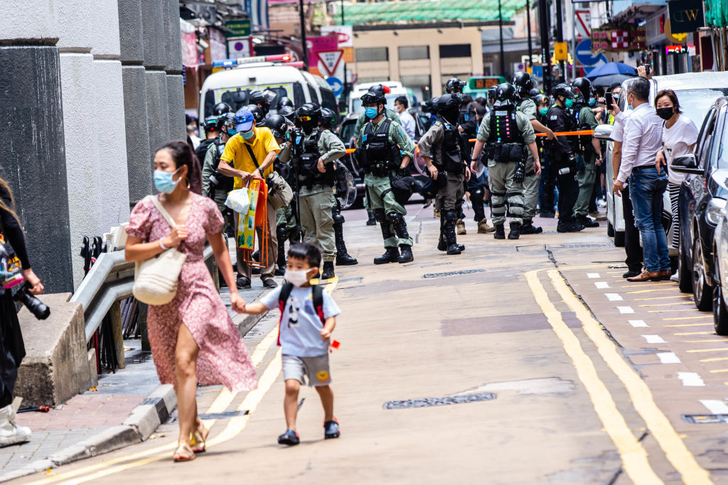 A woman walks her child away from riot police during the