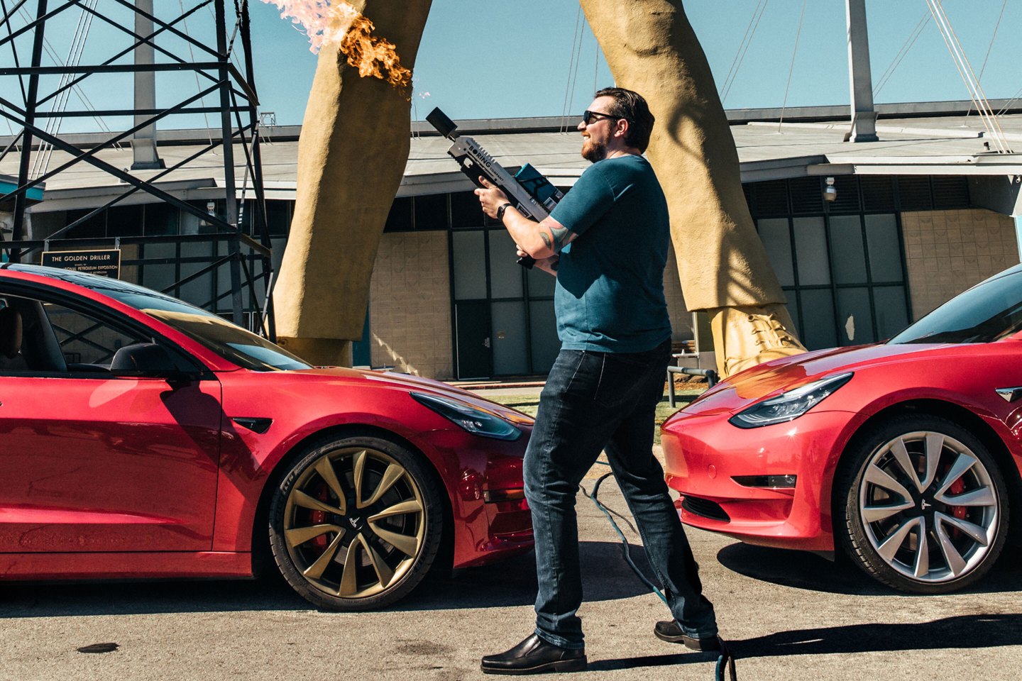 Man with boring company flamethrower in front of Tesla statue in Tulsa, Oklahoma.