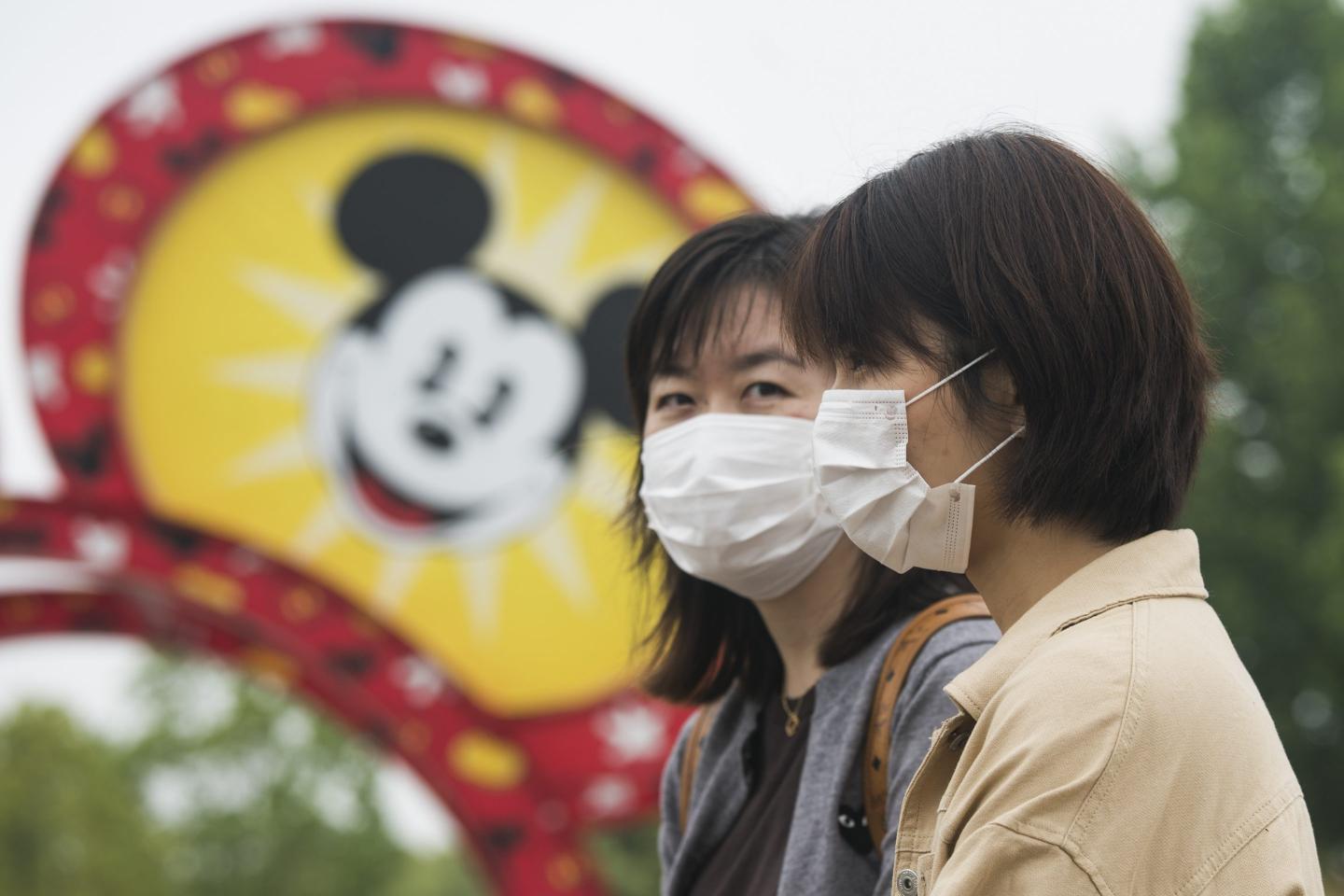 Two people wearing masks outside of Shanghai Disneyland Park.