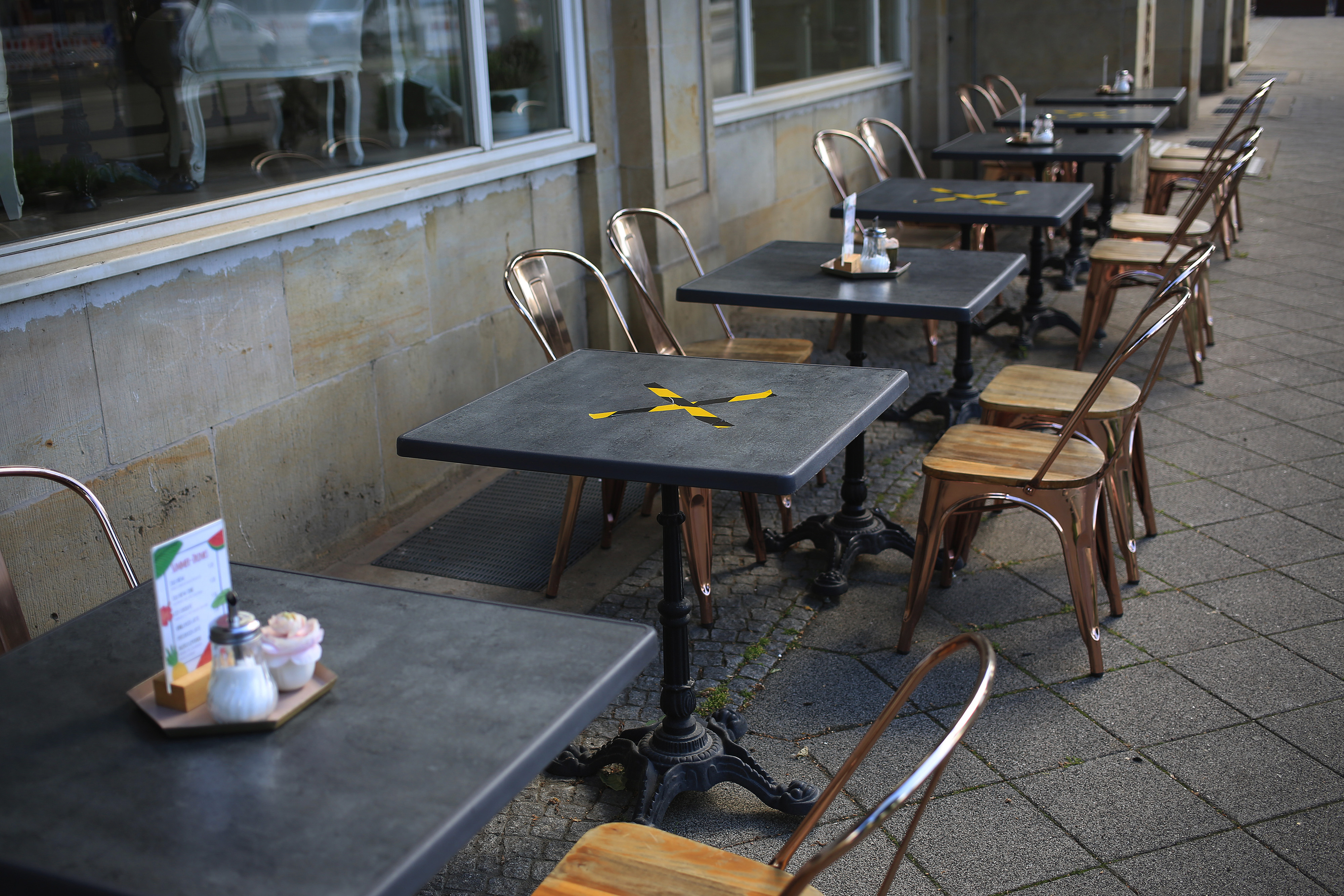 Tape markers indicate closed tables for social distancing on a cafe terrace in Magdeburg, Germany. On Wednesday, the OECD said that with a second wave of COVID-19, global GDP would drop by more than 7.5%, and about 40 million more people would lose their jobs.   Krisztian Bocsi—Bloomberg via Getty Images
