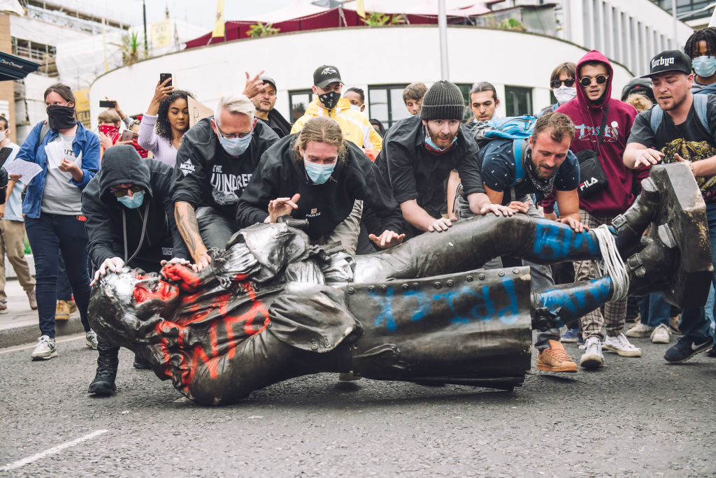 Black Lives Matter protestors roll the statue of Edward Colton, who was active in the slave trade, towards the harbor where they will later dump it.