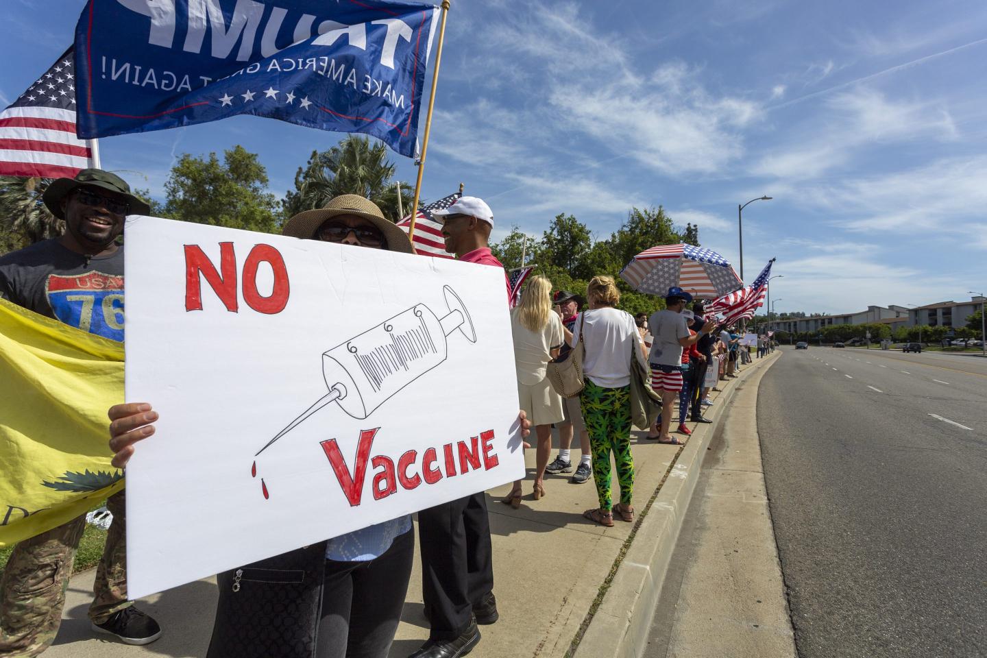 A protester holds an anti-vaccination sign as supporters of President Donald Trump rally to reopen California as the coronavirus pandemic continues to worsen, on May 16, 2020 in Woodland Hills, California.