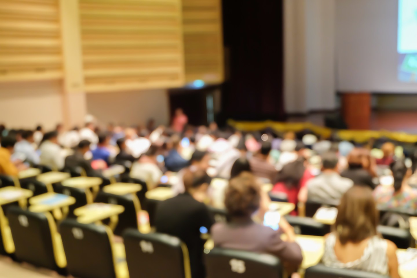 blurred focus group of student sitting for listening teacher explaining or sharing experience and knowledge in convention hall room , education concept