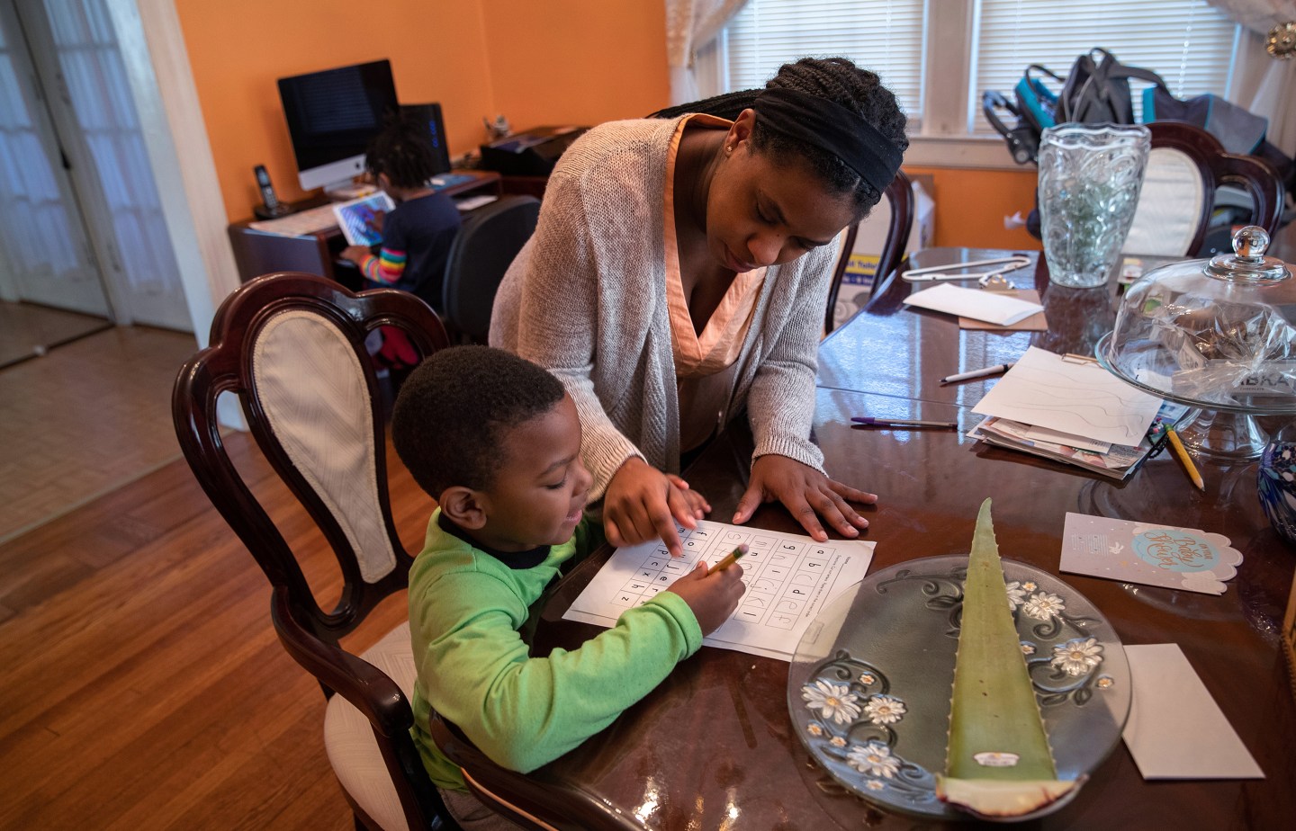 MOUNT VERNON, NY - MARCH 26: Geri Andre-Major helps her son Max, 5, with his school work on March 26, 2020 in Mount Vernon, New York. Andre-Major said she was furloughed as a pre-school teacher at Chelsea Piers Connecticut on March 13, four days after giving birth, and her maternity leave pay abruptly cut off as schools closed due to the coronavirus pandemic. Her husband was laid off as a chef consultant. The family left their apartment in New Rochelle, NY, hard hit by COVID-19, to live temporarily with Geri's parents. (Photo by John Moore/Getty Images)