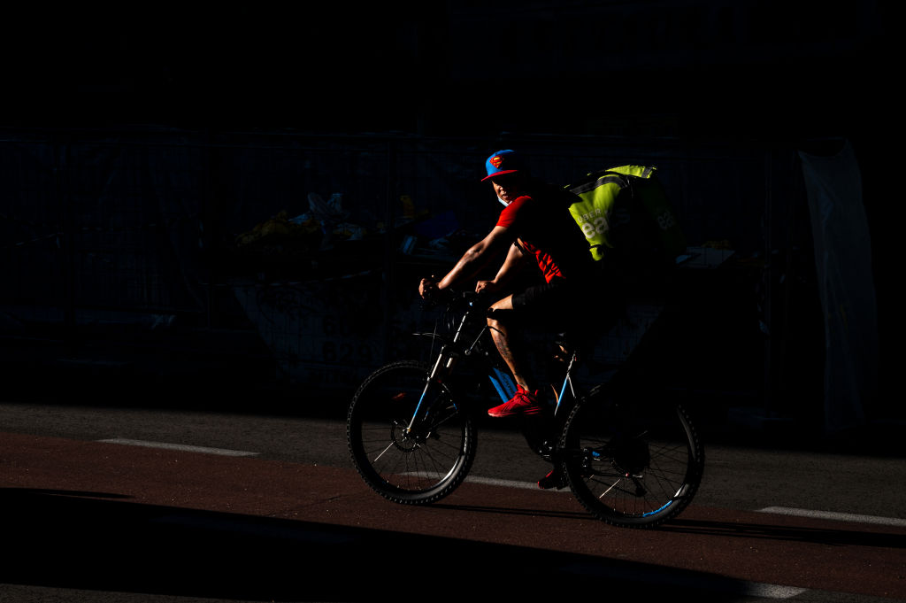 A delivery cyclist of Uber Eats company wearing a Superman
