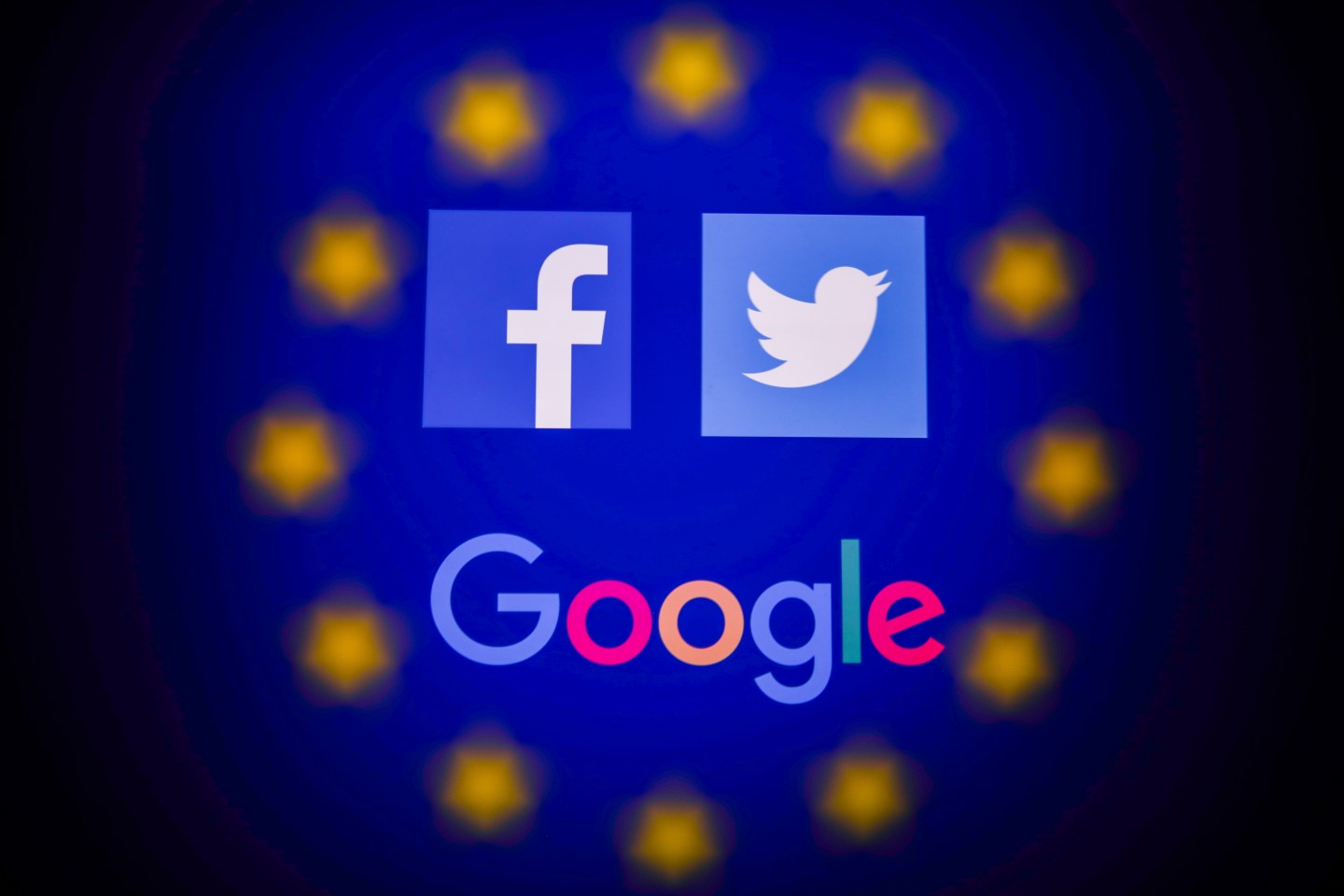 Facebook, Twitter and Google logos displayed on a phone screen and European Union flag displayed on a screen in the background are seen in this multiple exposure illustration photo taken in Poland on June 14, 2020.