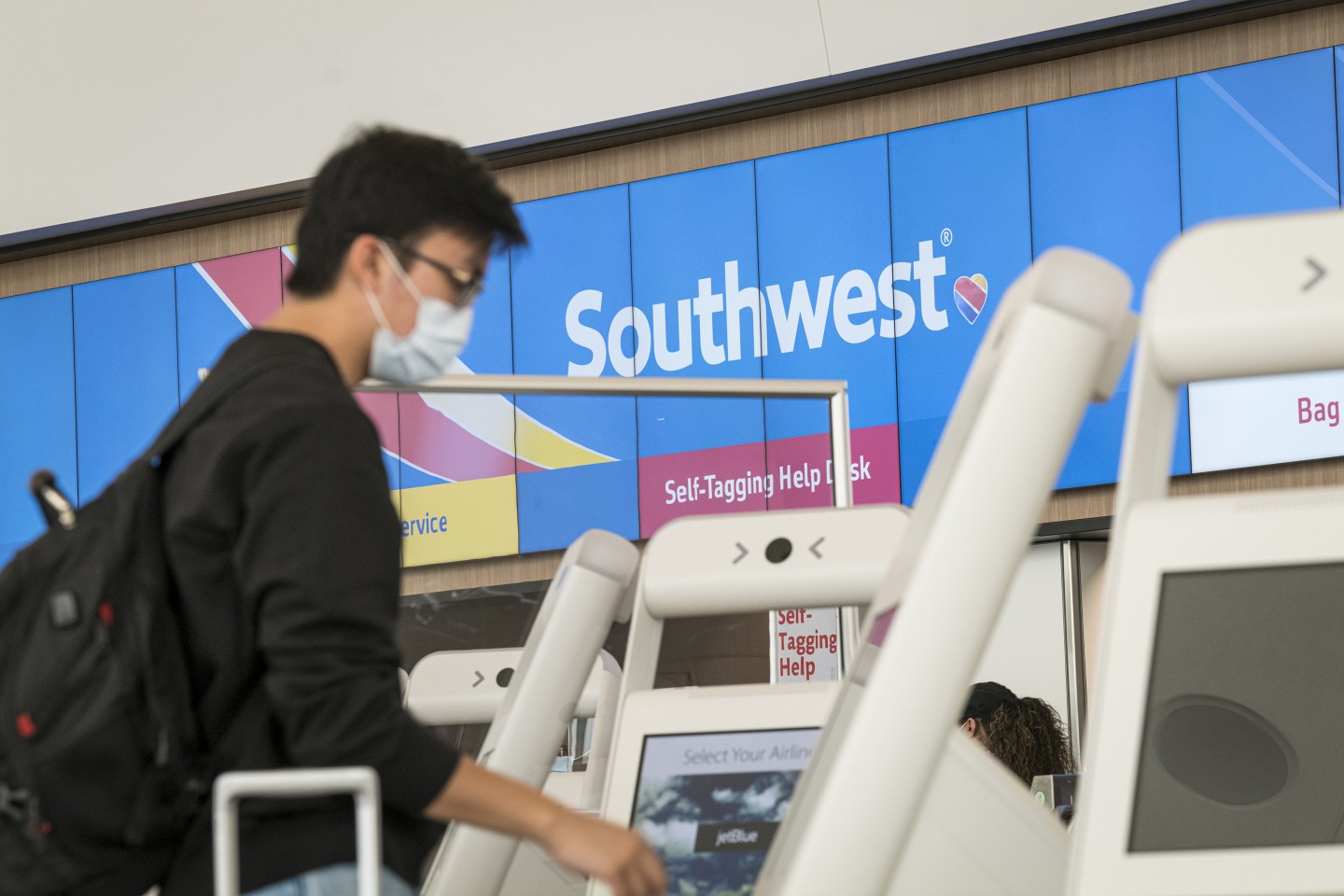 A traveler wearing a protective mask uses a kiosk at the Southwest Airlines Co. check-in counter at San Francisco International Airport (SFO) in San Francisco, California, U.S., on Wednesday, July 15, 2020. Southwest Airlines Co. is scheduled to release earnings figures on July 23. Photographer: David Paul Morris/Bloomberg via Getty Images