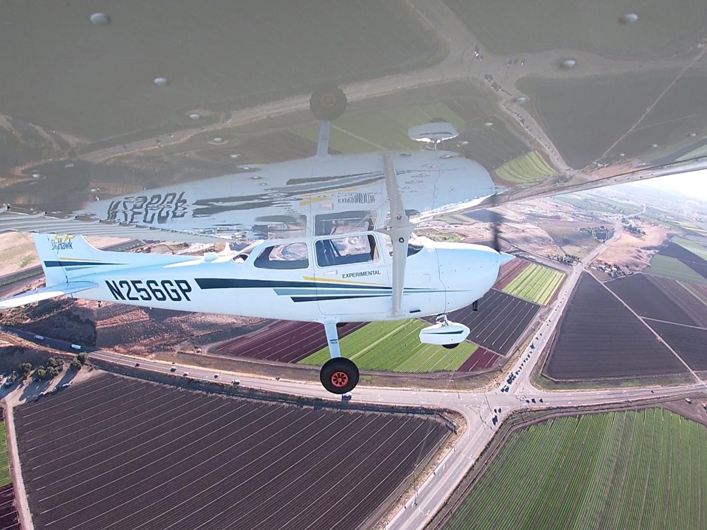 Cessna 172 flying without a pilot, banking over farmland.