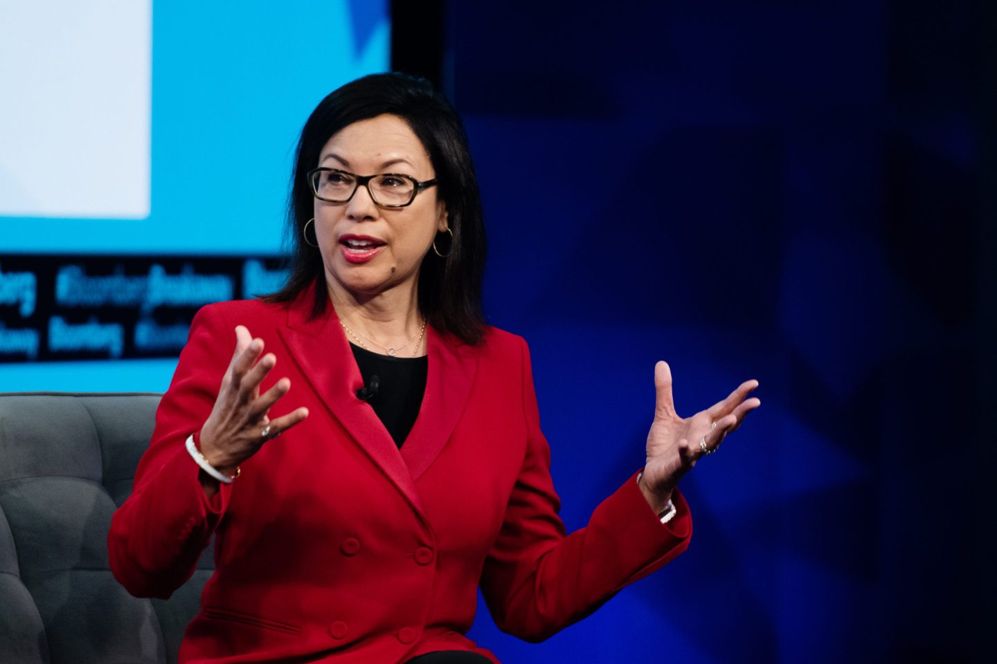 woman in red suit jacket speaking onstage