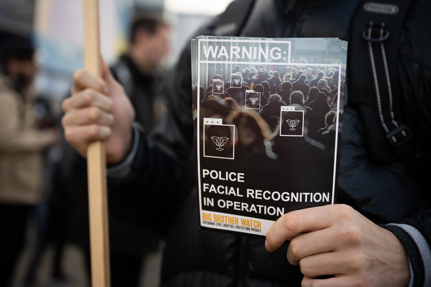 A man holds a sign during a protest against the use of police facial recognition cameras at the Cardiff City Stadium for the Cardiff City v Swansea City Championship match on January 12, 2020 in Cardiff,