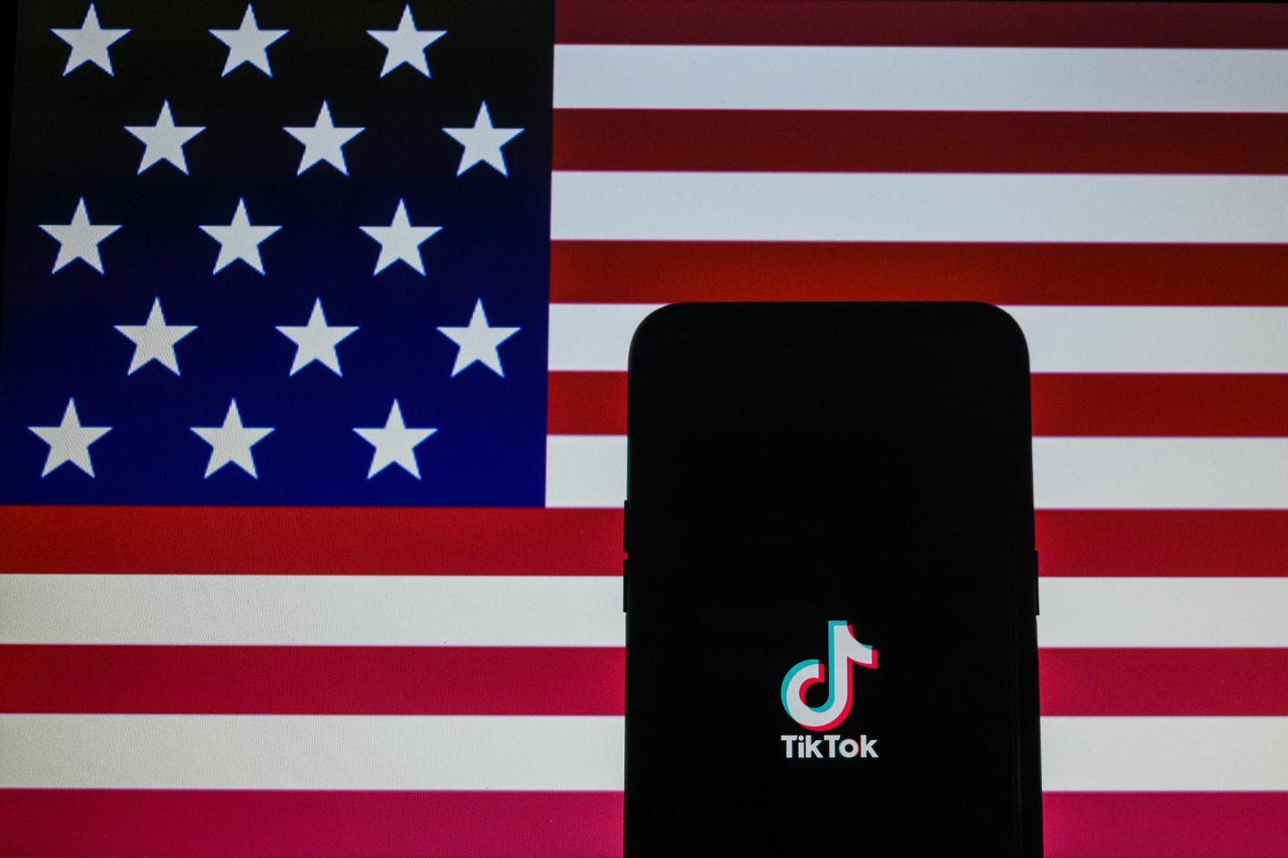 A photo Illustration of Tiktok logo on mobile device with USA flag in background in Kolkata, India, on August 29, 2020.