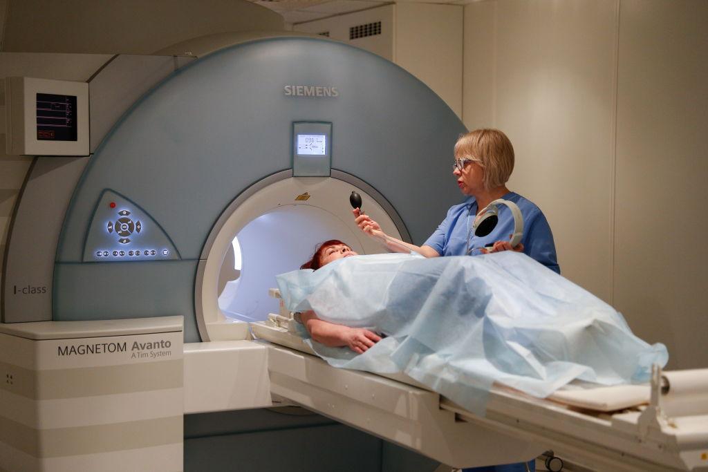 Women being placed into an MRI scanner by a nurse.