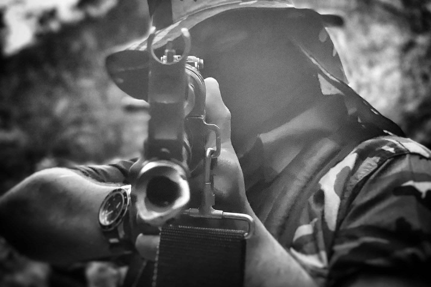 In the Sinaloa mountains, a cartel soldier points a gun at the camera.